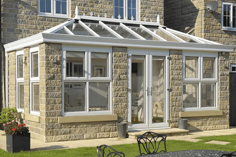 Exterior view of white uPVC conservatory with glazed roof and brick sections 
