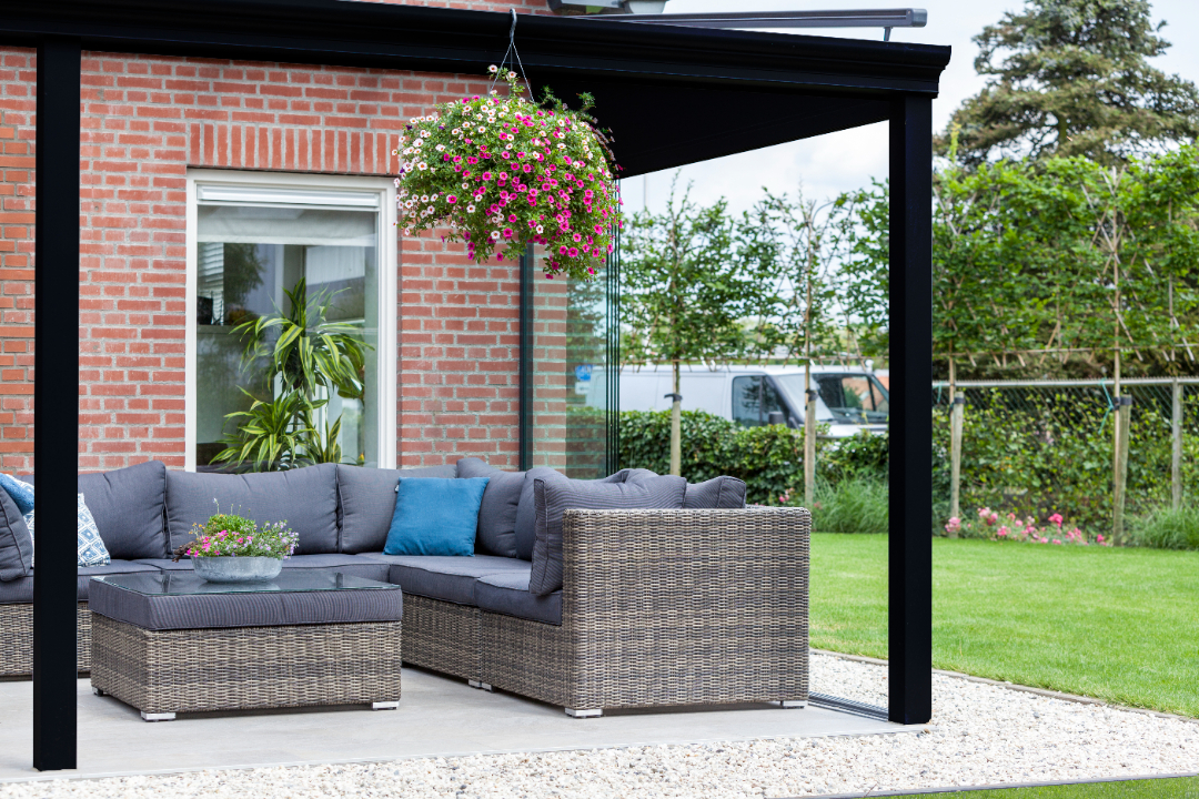 Create a stunning outdoor living space with a Deponti veranda, featuring comfortable lounge seating and vibrant hanging flowers for a touch of elegance. Perfect for alfresco dining or relaxing.