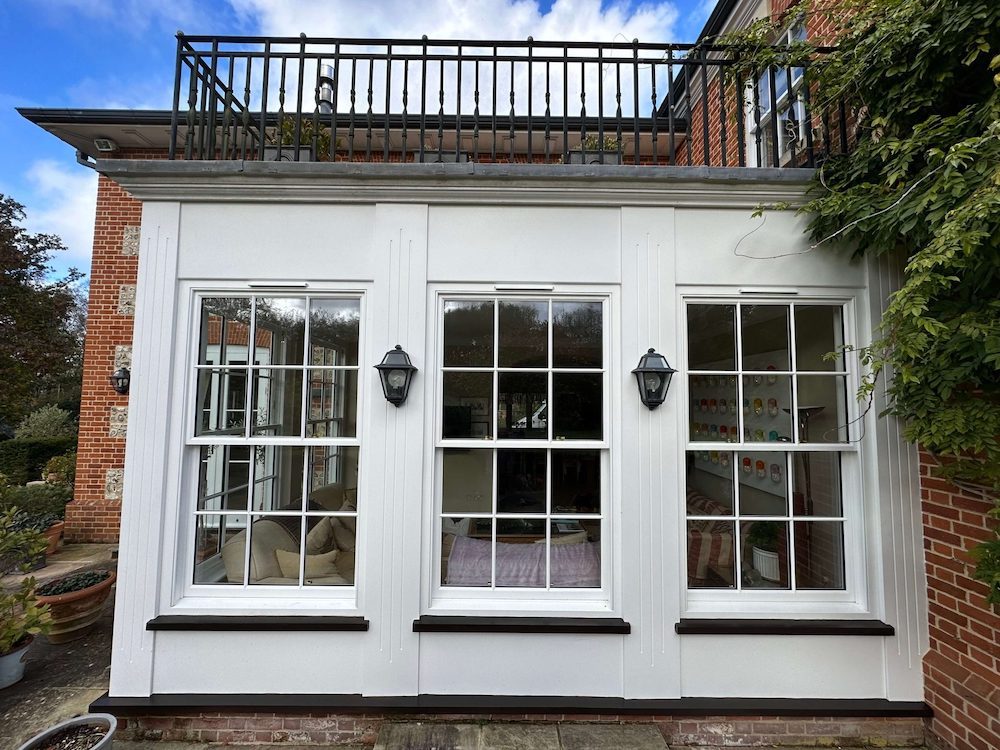 White orangery with sash windows and a roof terrace above
